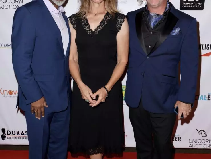 Three people are smiling and posing together on the red carpet at an event focused on ending child exploitation.