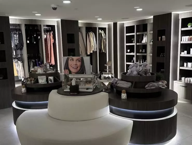 A modern boutique interior with curved display shelves, assorted products, and a large promotional image of a woman's face.